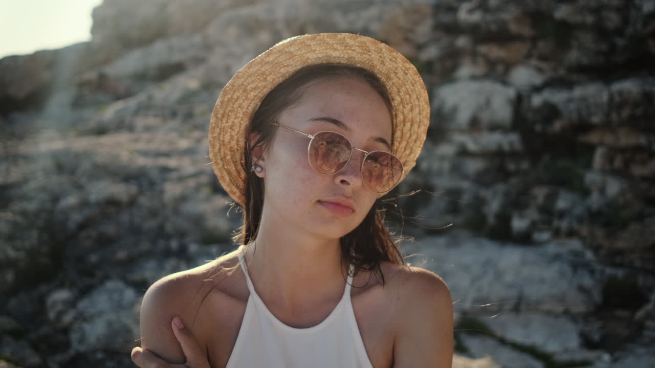 женщина с соломенной шляпой и солнцезащитными очками у скал