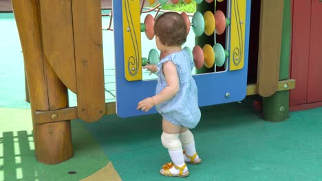 cute toddler at playground learning and having fun spinning colorful disks, korean-ukrainian multi-ethnic baby girl