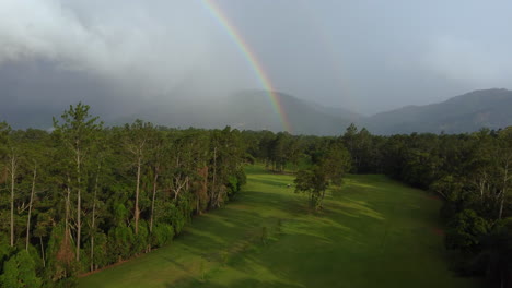 golf course aerial view with a beautiful rainbow, mountains and rainstorm