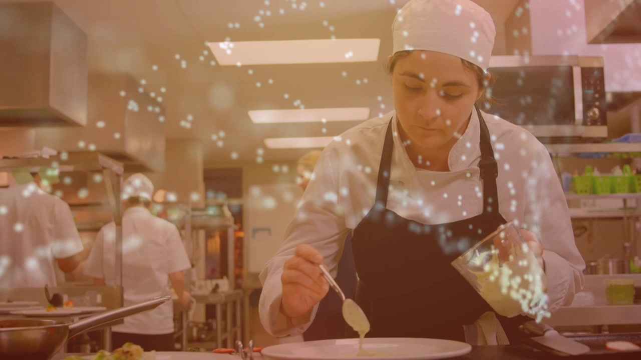 Cuoca che versa salsa chiara da una brocca su un piatto bianco, la cucina brilla pronta per il servizio.