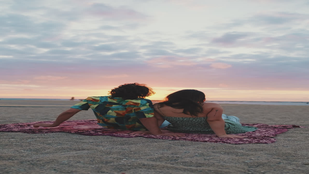 Una pareja viendo la puesta de sol en la playa