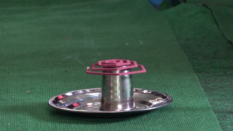 a mosquito coil smoking on a tin plate to keep the mosquitoes away