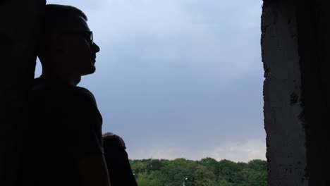 silhouette of a man sitting on a window sill of a building and singing