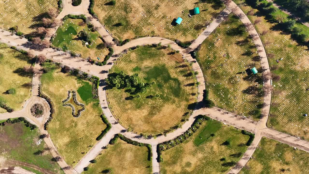 Ascending spiral drone shot of circular park pathways with geometric design, top-down bird's eye view, urban green space, Santiago, Chile