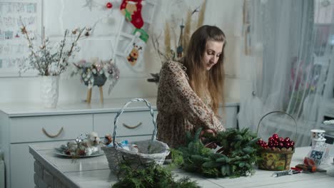 making rustic christmas wreath. woman holding green branches on rustic wooden background. seasonal holiday workshop online, making festive decorations at home