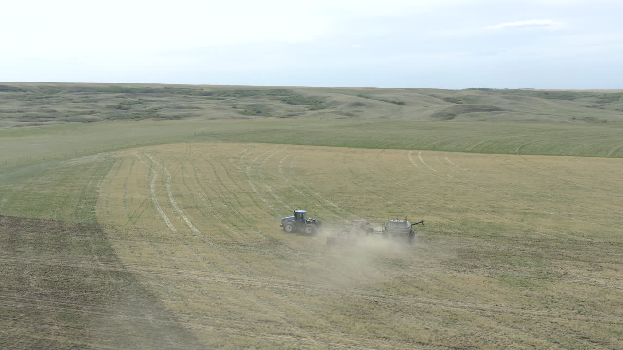 캐나다의 거대한 들판에서 트랙터 파종, 공중 드론 샷 추적