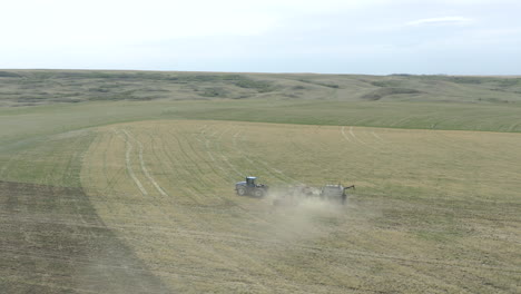 tractor seeding in huge field in canada, tracking aerial drone shot