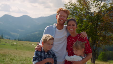 familia feliz abrazando colina de montaña de cerca. padres descansando con los niños en la naturaleza