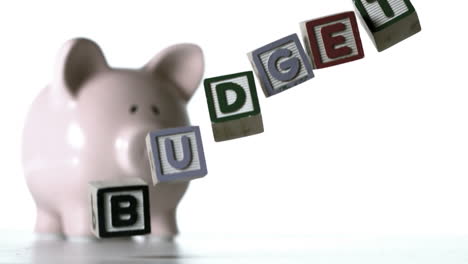 blocks spelling budget falling over in front of a piggy bank