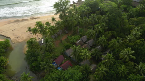 aerial shot looking down on homes in thailand as waves crash on the beach