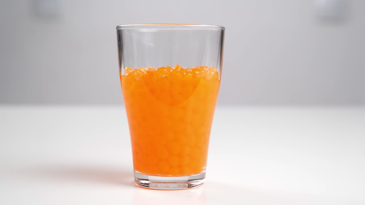 Orbeez - balls that grow in water pour into a glass of water.