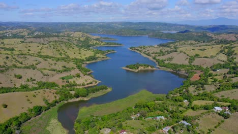 Aerial-flyover-Bao-River-surrounded-by-green-hilly-landscape-during-sunlight---Dominican-Republic-at-daytime