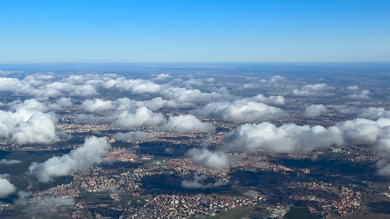 Vista aerea laterale della città di Madrid dal cielo, con una veduta del centro e dei dintorni, con piccoli cumuli sparsi che fluttuano sopra la città