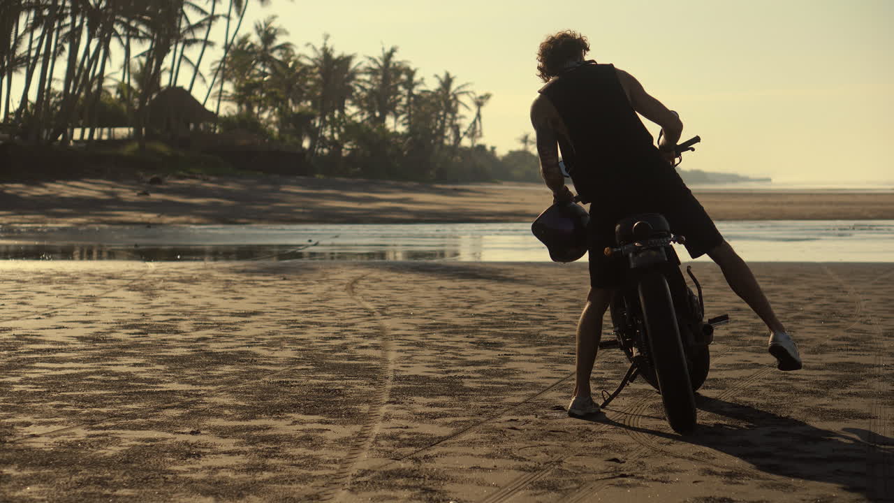 Man on motorcycle on a beautiful beach at sunrise