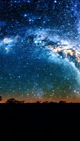 a large, curved, orange and white sky with a dark background. the sky is filled with stars and the horizon is dotted with trees