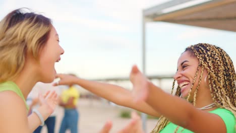 happy friends embracing and laughing on the beach