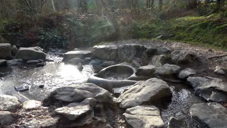 Shiny-river-flowing-through-primitive-weathered-eroded-smooth-stone-worn-ceremonial-basin