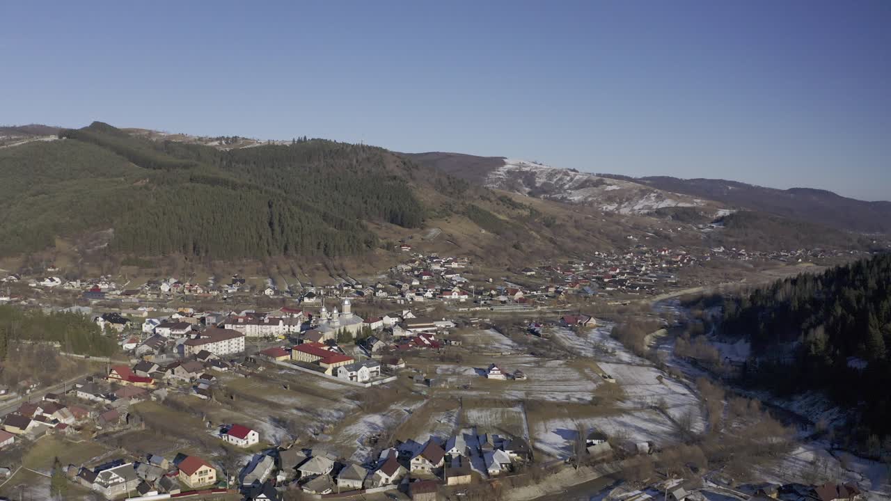 vista de drones de padure - comunidad en el valle debajo de montañas bordeadas de pinos