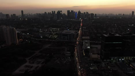 A-cinematic-aerial-shot-of-the-busy-orange-coloured-arterial-road-and-intercrossing-overpass-during-twilight