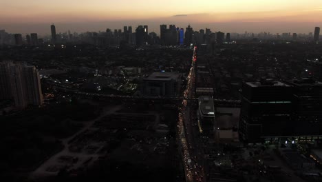 Una-Toma-Aérea-Cinematográfica-De-La-Concurrida-Carretera-Arterial-De-Color-Naranja-Y-El-Cruce-Del-Paso-Elevado-Durante-El-Crepúsculo