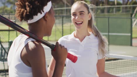 Video-of-happy-diverse-female-tennis-players-holding-rackets-and-talking