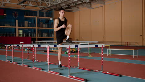 male athlete jumping hurdles