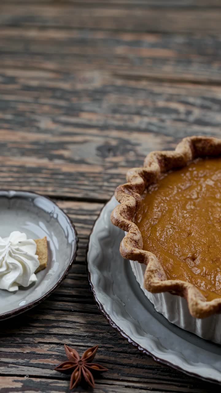 Rustic top-down video shot of a pumpkin pie on a wooden table, showcasing its textured crust