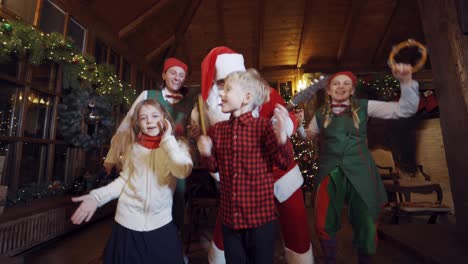 happy children with fairy characters dancing in christmas decorated room. christmas celebration with musical instruments inside the santa's residence.