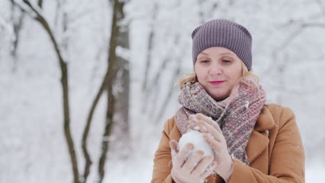 a woman sculpts a snowball and throws it in the direction of the camera winter fun