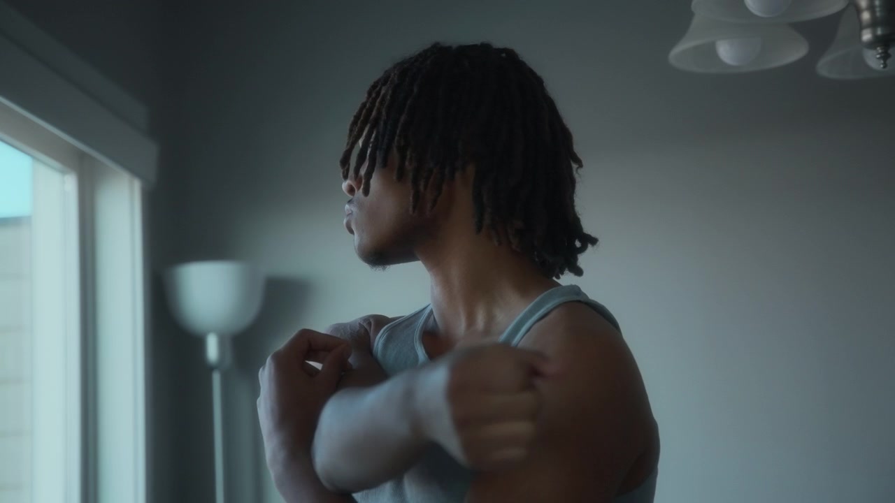 Young man stretching next to a window at home