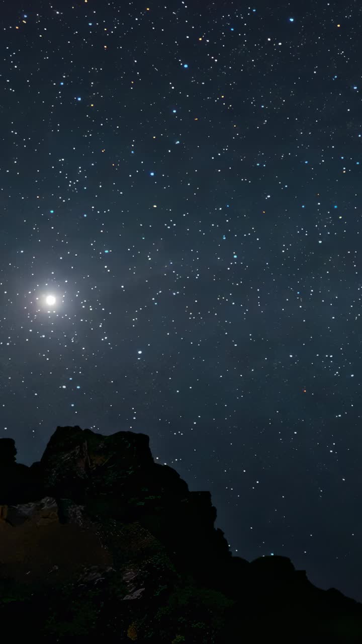 Vertical video: Starting timelapse, cam filming stars at cliff tracing star motion with moon, rock