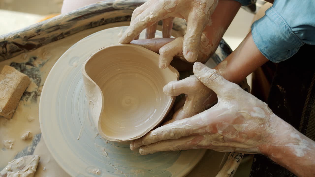 Hands shaping a heart-shaped bowl on a pottery wheel