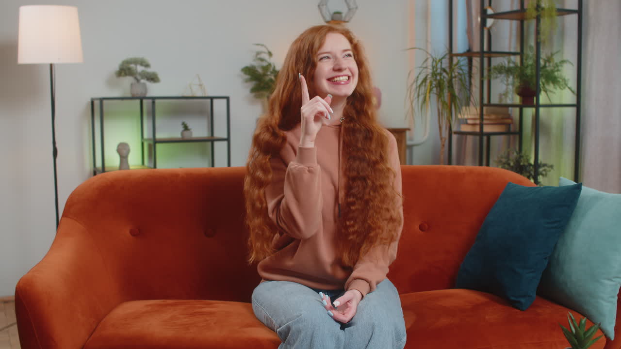 사려 깊고 영감을 받은 여성은 긍정적인 몸짓을 하고 손가락을 올리며 집에서 창의적인 아이디어를 떠올렸다.