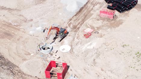 excavation digger bulldozer preparing concrete pipe aerial from above view on housing development construction site orbit right