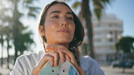 skater woman straightens hair at bright sun street closeup. girl enjoying summer