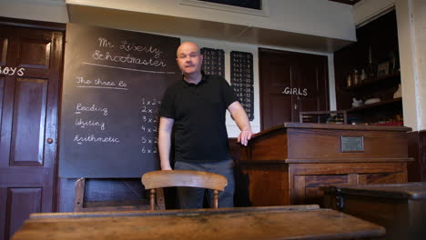 wide shot of a male teaching in old victorian school classroom