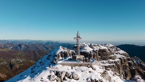 hikers on summit cross of resegone mountain in northern italy