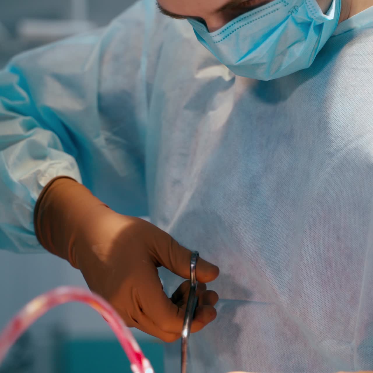 Professional work of surgeon. Male doctor in medical uniform and mask using surgical instruments while doing an operation. Medical concept.