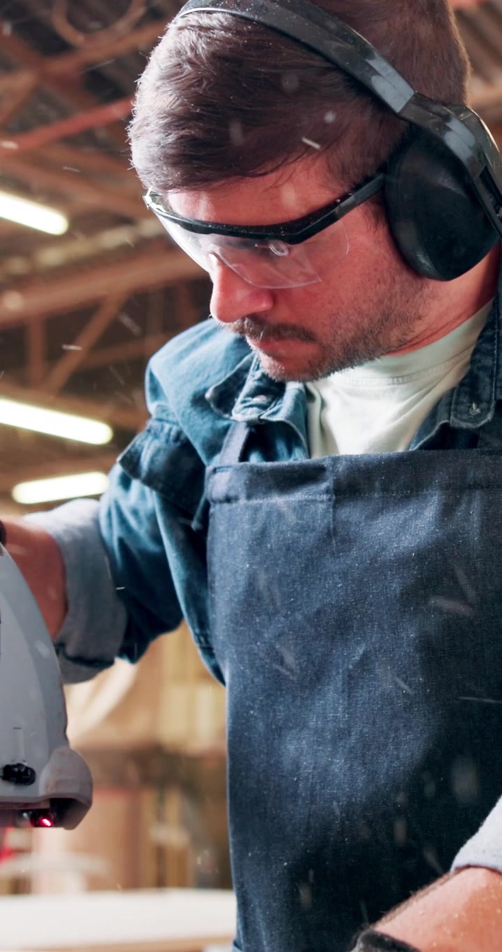 Carpenter Using Miter Saw to Cut Wood in Workshop