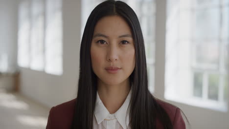 portrait of professional asian business woman looking at camera serious confident independent female in apartment windows background real people series