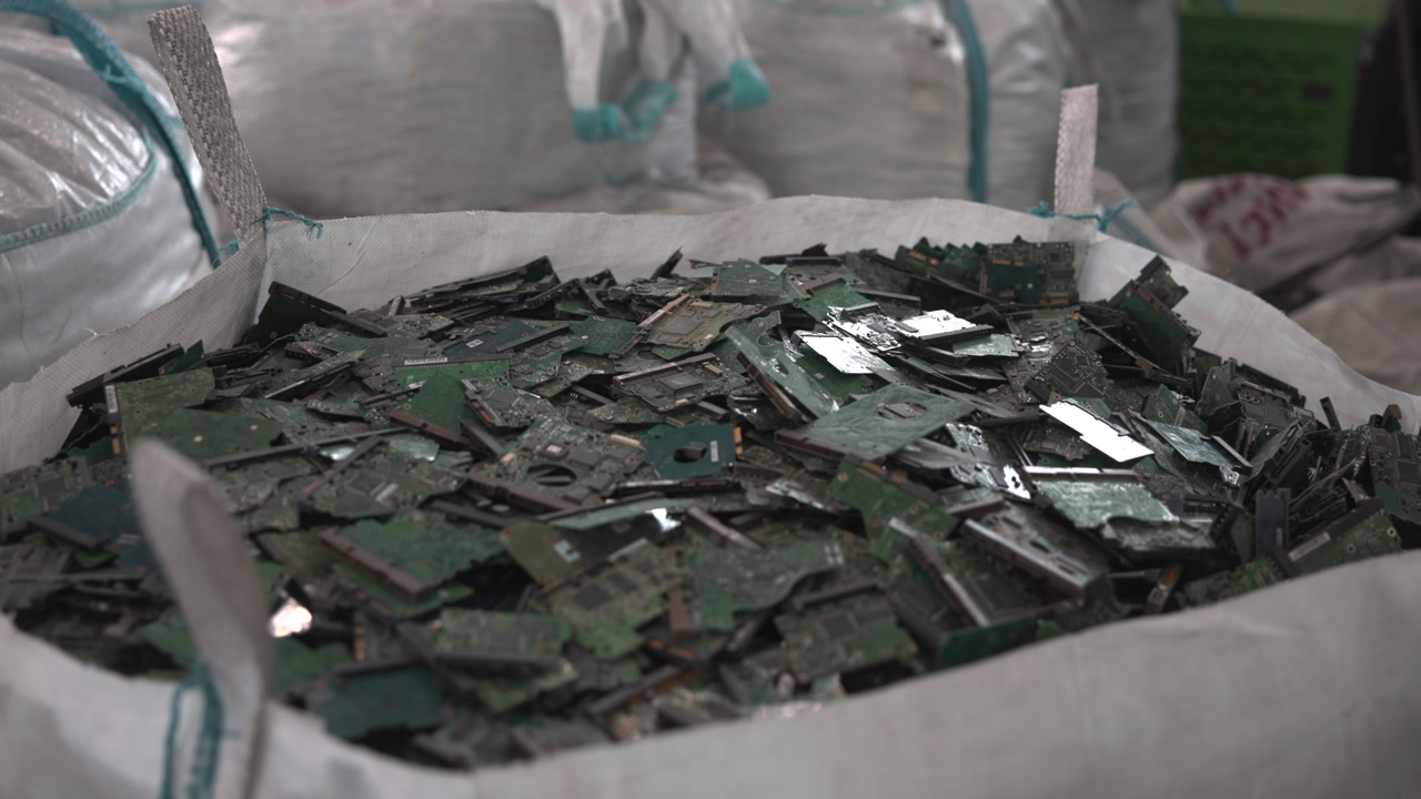 Shredded Green Circuit Fragments Inside Large Bulk Bag, Reflective Flakes And Broken Board Shards, Closeup . Media