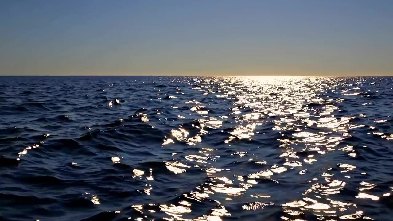 夕焼けの穏やかな海の波に反射する太陽の光