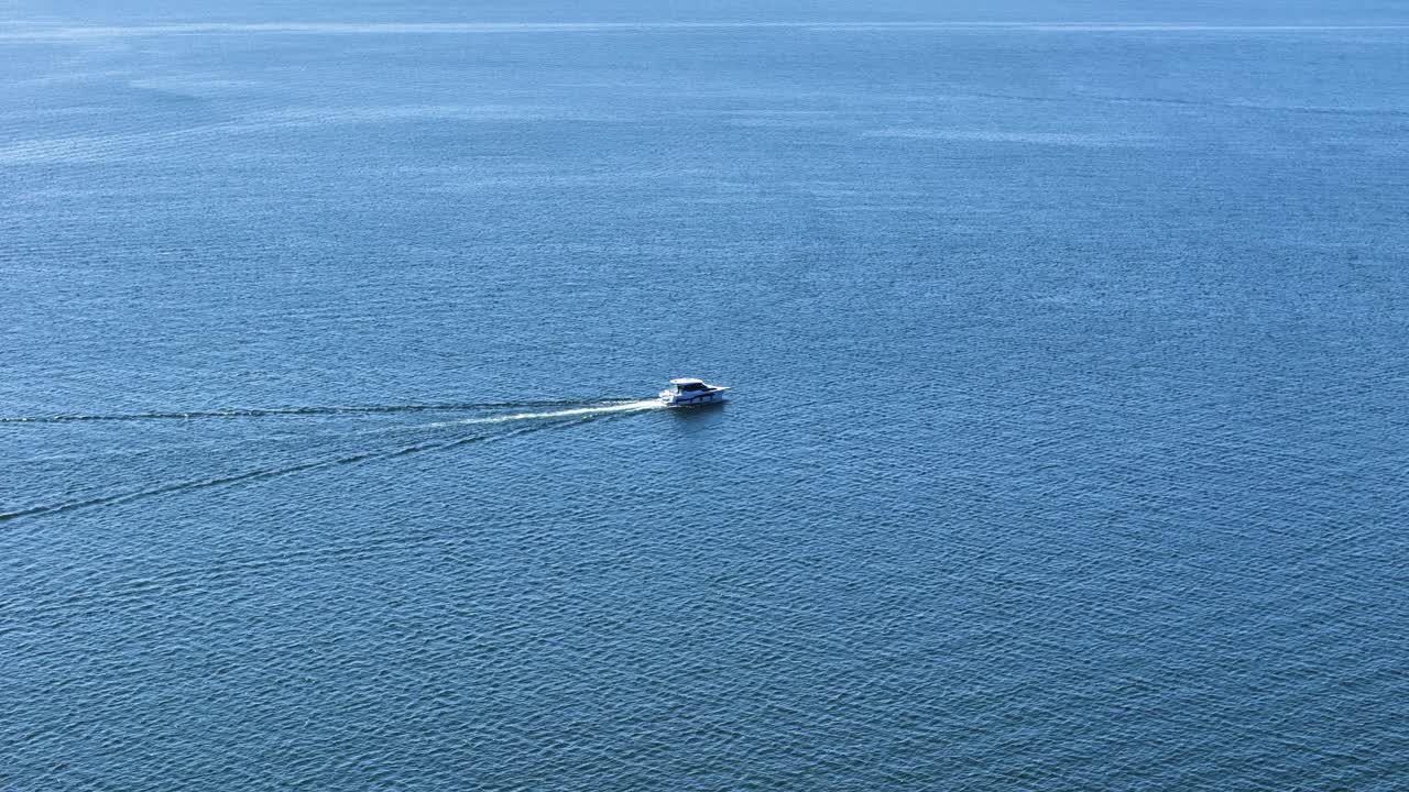 Private boat speeding through calm lake near Gizycko, aerial view