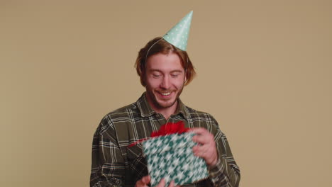 feliz joven abriendo caja de regalo, desenvolviendo sorpresa de cumpleaños satisfecho con el mejor bono presente