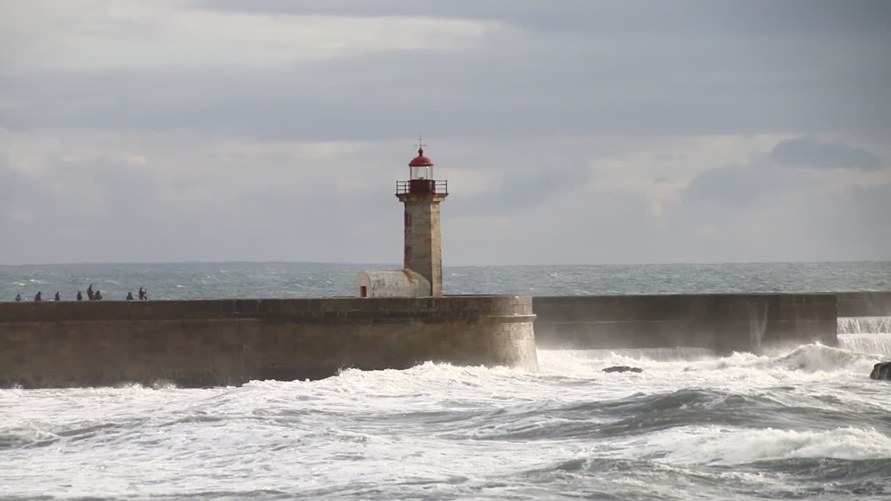 las olas aplastan el faro de oporto en una noche nublada y ventosa