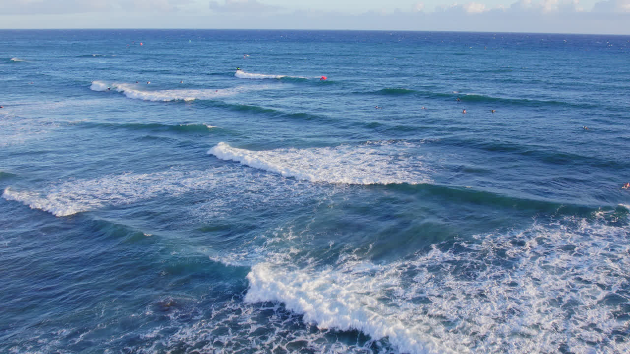 imágenes de drones que se dirigen hacia la costa que muestran las olas blancas del océano azul del océano pacífico con una salpicadura de surfistas y kite boarders esperando una ola cerca de oahu hawai