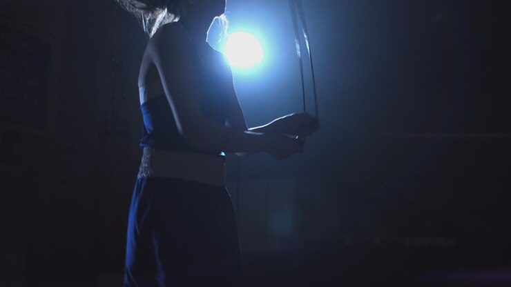 Young beautiful woman professional boxer in training in the gym jumping rope medium size slow motion