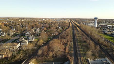 Railroad-tracks-leading-through-small-midwest-town-in-USA,-aerial-view