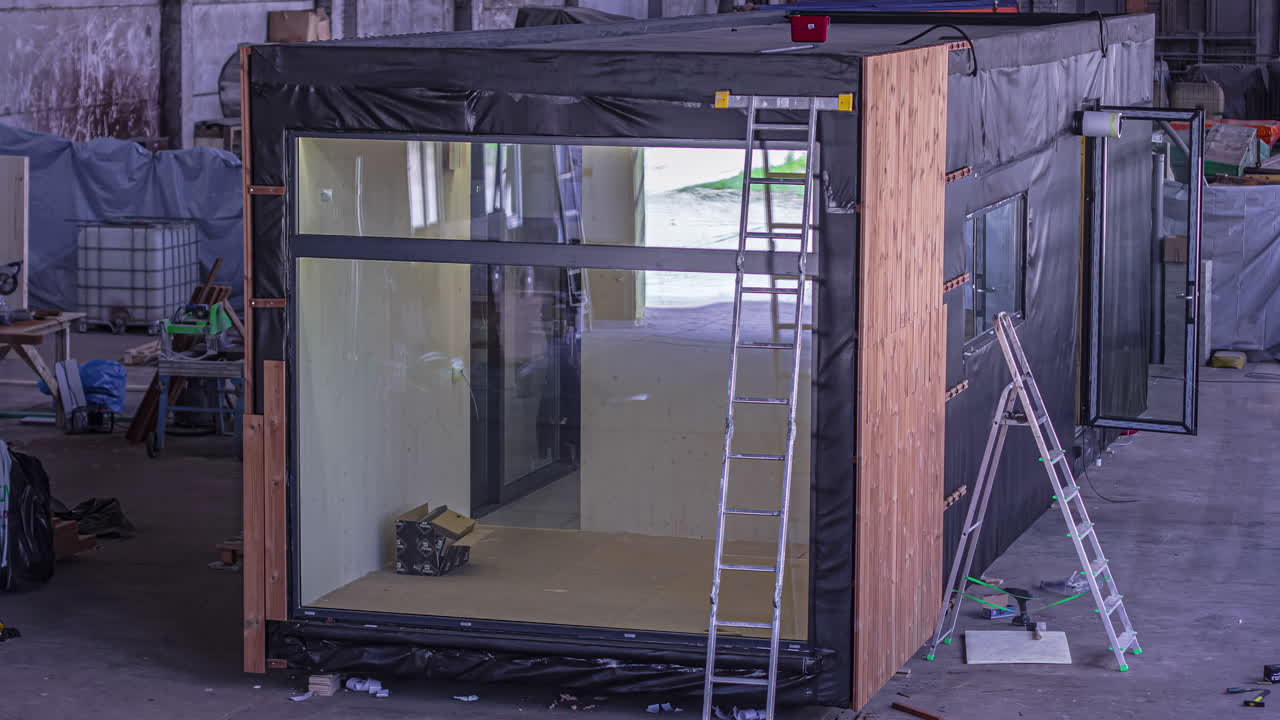 toma estática de la construcción del exterior de una pared de madera de una casa contenedor en el fondo durante el día.