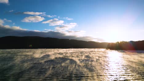 fog on lake, golden sunlight rising, steam fog rising from a lake, early morning arial drone shot 60fps, with blue sky